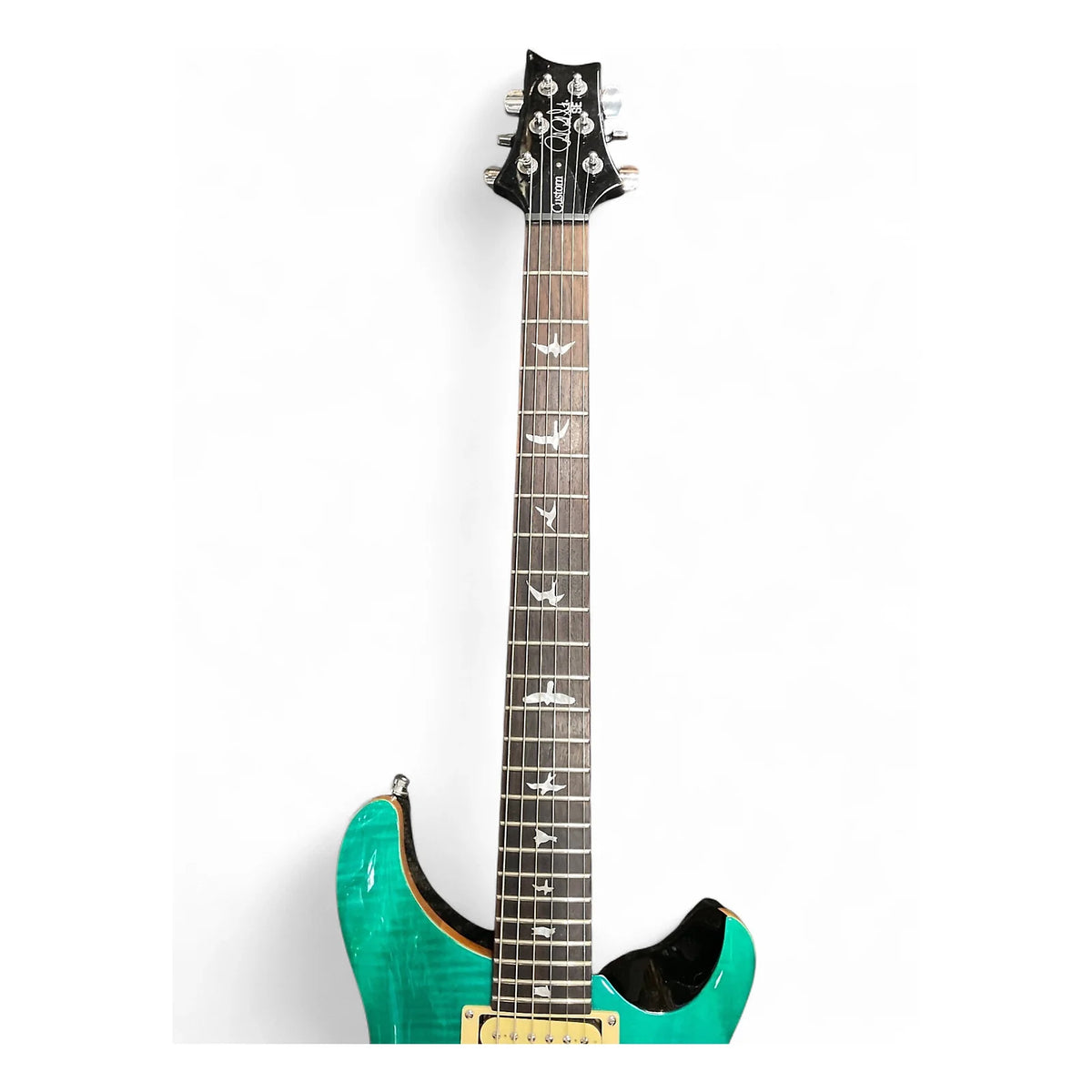 A teal green electric guitar with a dark wood neck and silver inlays, shown from a high angle against a plain white background.