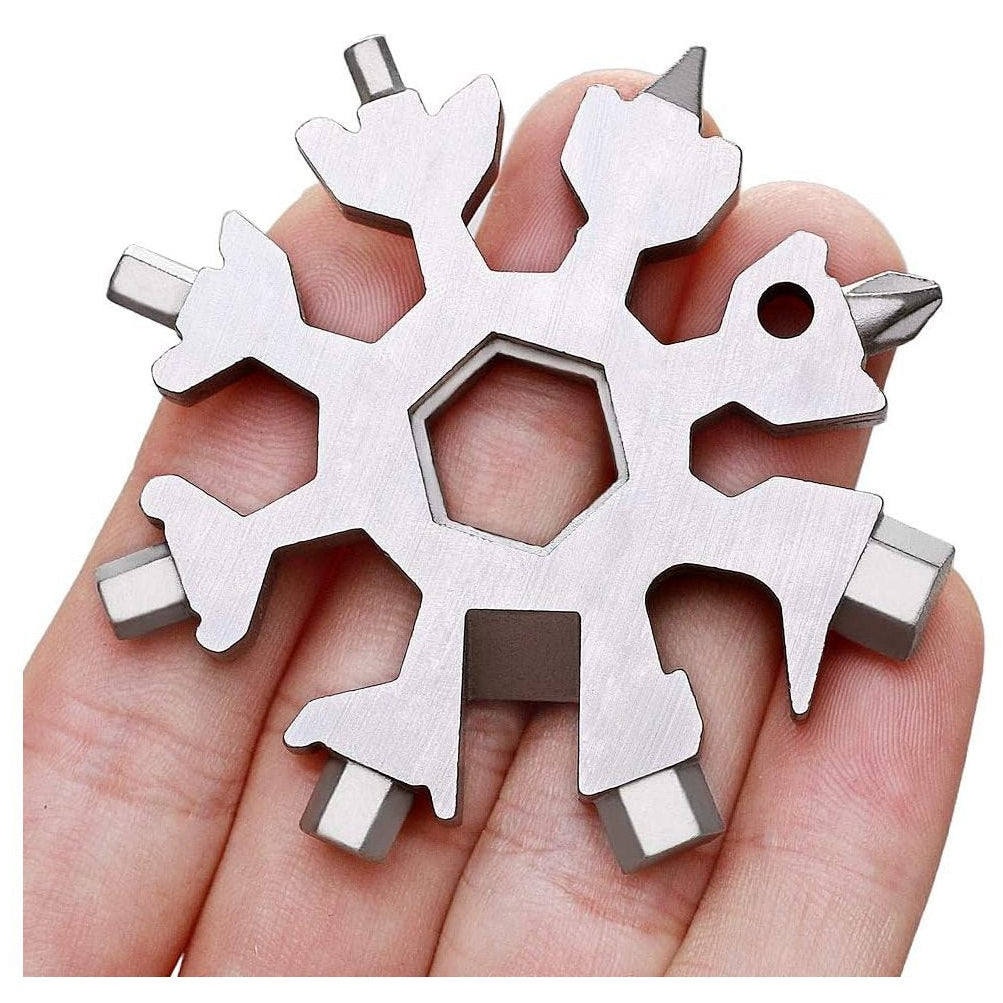 Metal snowflake-shaped multitool held in a hand against a white background