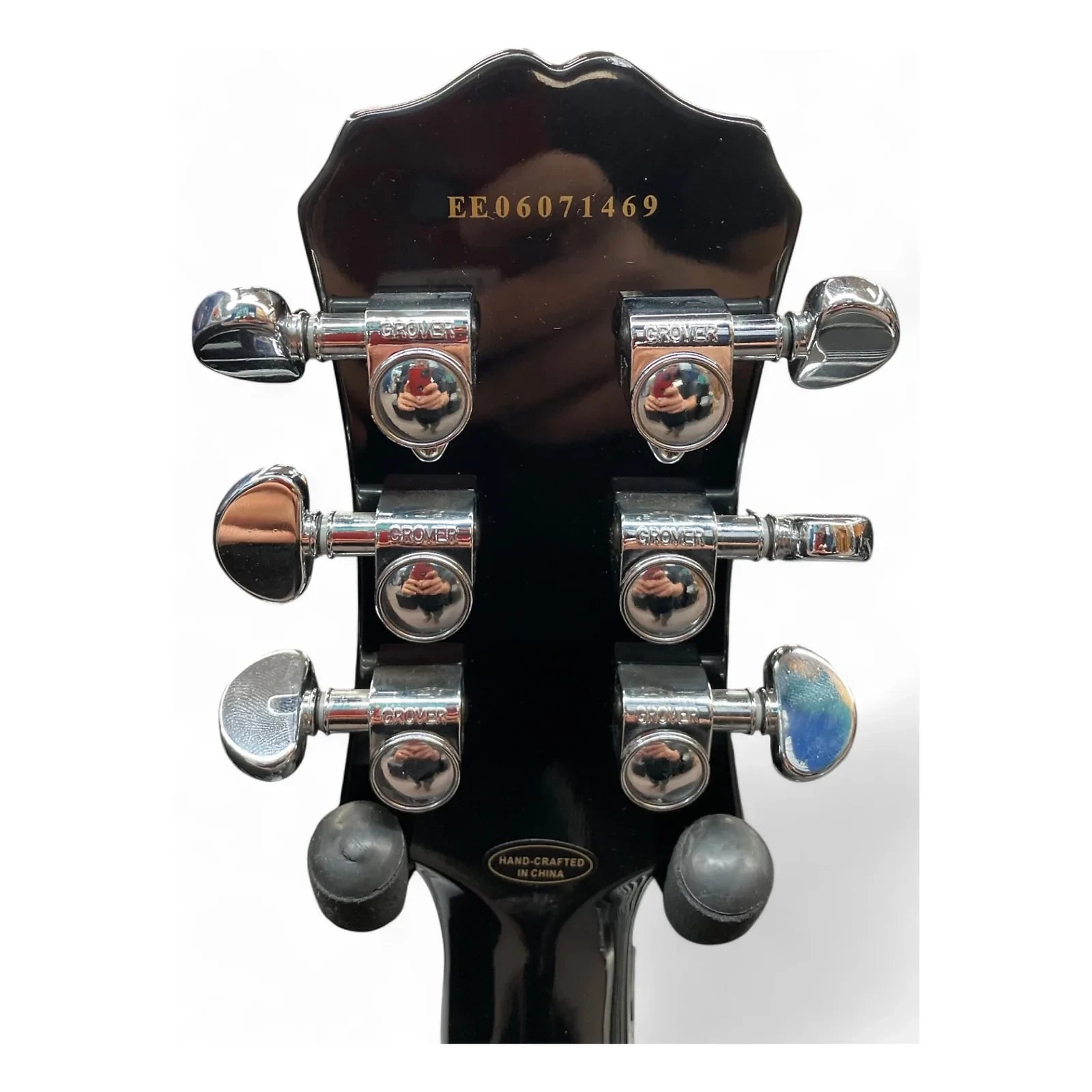 Close-up of a guitar headstock with tuning pegs on a white background