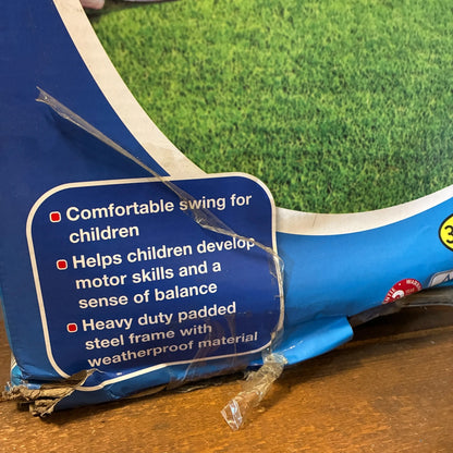 Blue swing set with safety label on grass and wooden floor