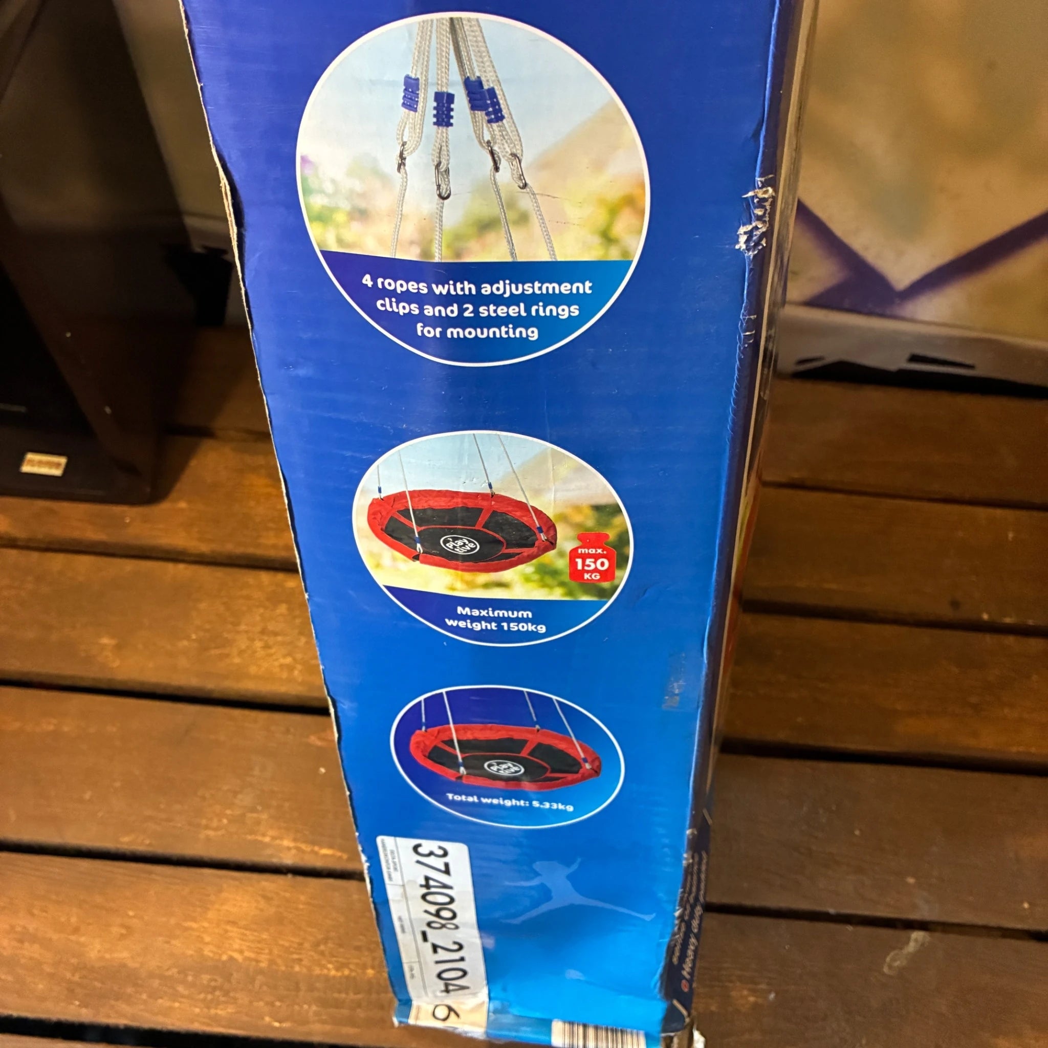 Blue packaging of a trampoline with product details on a wooden surface