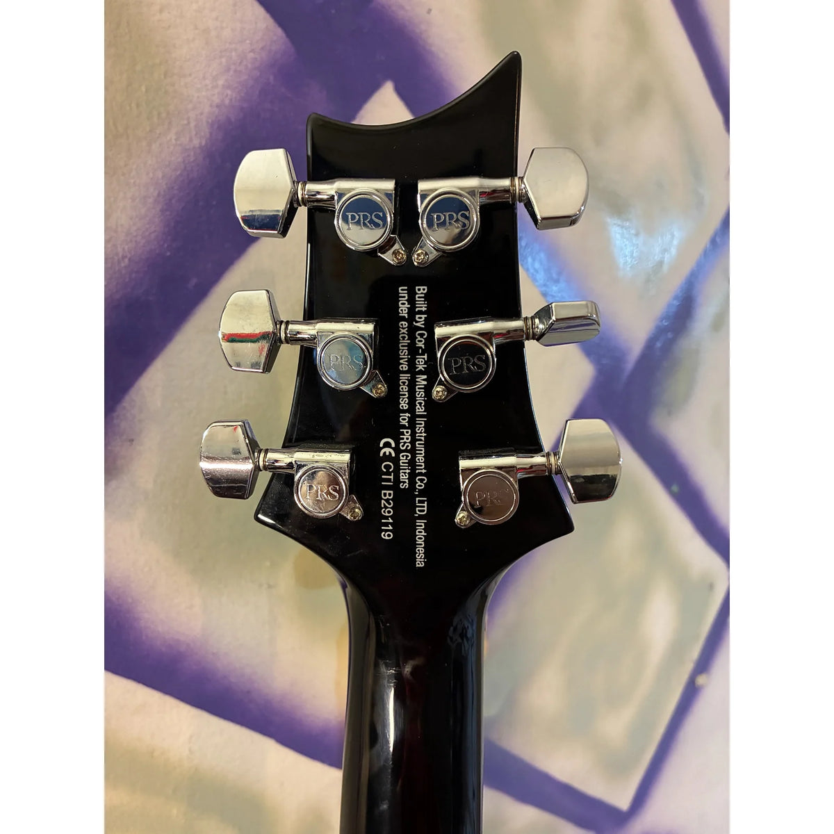 Close-up of the headstock of a black electric guitar, showing the PBS logo on the tuning pegs and model text for a 2019 Gibson Les Paul Custom Edition.