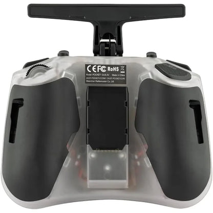 A close-up of a remote control transmitter with a transparent casing, black grips, and a black top handle, showing a central battery compartment and regulatory labels.